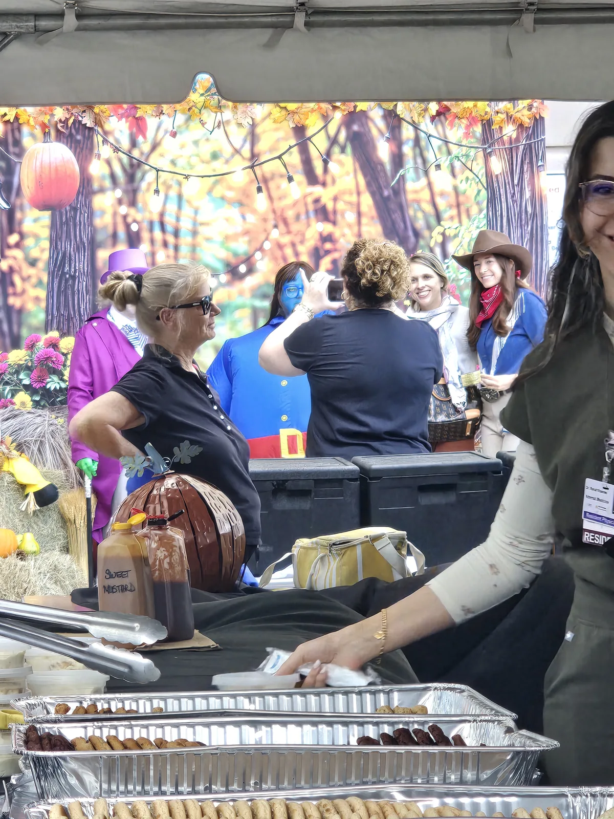 Fall Festival guests in costumes beside the autumn photo backdrop